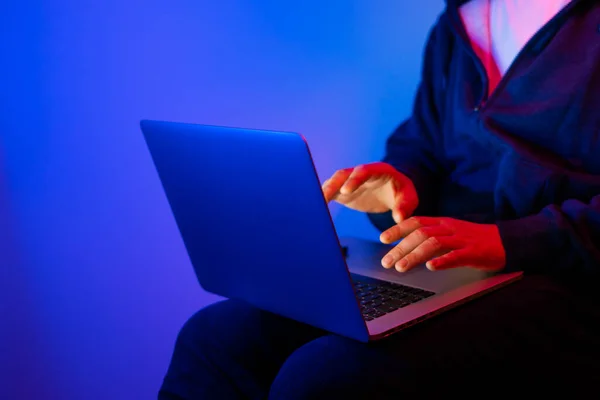 Laptoplu genç adam. Kırmızı ve mavi neon ışık