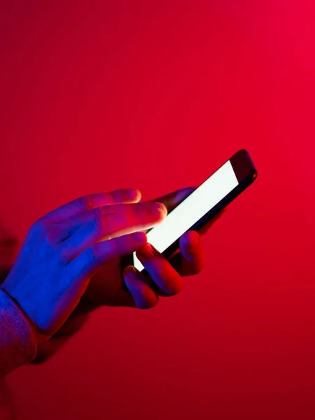 Akıllı telefonlu bir erkek. Boş beyaz ekran. Model-up. Kırmızı ve mavi neon ışık.
