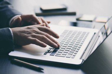 İşadamı dizüstü bilgisayarda çalışıyor ve ofisindeki mali bilgileri analiz ediyor. Bilgisayar klavyesinde yazan erkek ellerini kapat