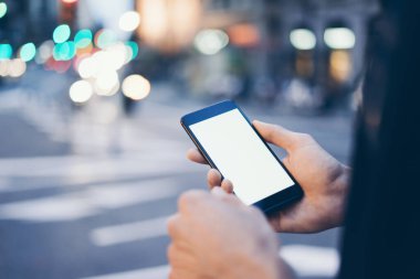 Erkek elinin boş ekranlı modern akıllı telefonu tutarken yakın plan görüntüsü. Model mesaj ya da içerik için hazır. Cep telefonlu bir adamın elleri. Boş ekran. Gece Caddesi, Bokeh Light