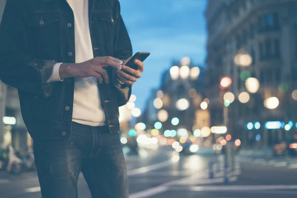 Gece vakti akıllı telefonlu bir erkek, internette ya da sosyal ağlarda arama yapıyor, hipster adam sohbete SMS mesajı yazıyor, sahte ışıklar...