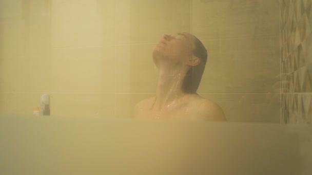 Kvinna tar en dusch, njuter av vattendroppar uppifrån. Närbild, slow motion — Stockvideo