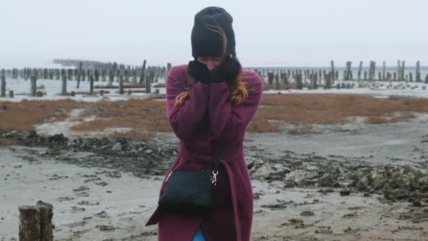 Mar de invierno, fuerte viento, chica se congela, ríe y baila en un día nublado sobre el fondo del muelle, metraje medio, en cámara lenta — Vídeo de stock