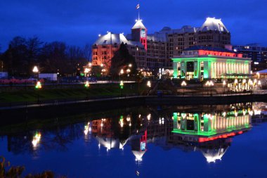 Victoria BC, Kanada ve suya yansıyan Noel ışıklarıyla dolu güzel iç limanı. Grand Pacific Oteli ve içinde John Bateman Merkezi bulunan Buharlı Gemi Binası da limana yansıyor..
