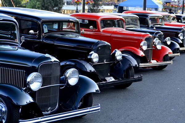 Classic cars lined up on street.
