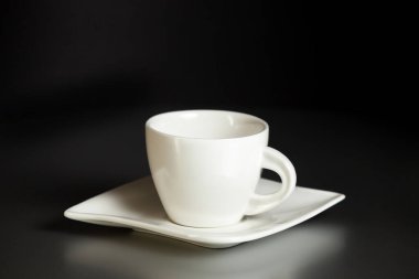 Kahve fincanı ve çay tabağı gri bir masada, siyah bir duvara karşı. Kahve molası, dinlenme. Yakın plan.. 