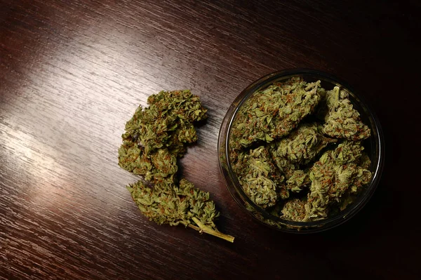 Marihuana tomurcukları deposu. Kahverengi ahşap arka planda çiçek açan tıbbi kenevirler, izole edilmiş. Kenevir rekreasyonu, tıbbi kullanım, yasallaştırma. 