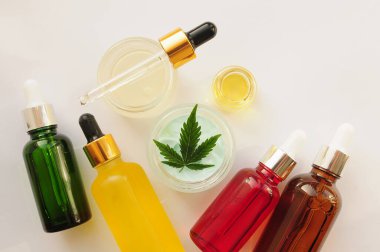 Marihuana yaprakları, cbd yağı, kozmetik krem. Kozmetolojide esrar özütü. Düz zemin, barut arkaplan. Ev rahatlaması, spa eğlencesi, eğlence terapisi..