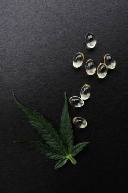 CBC yağlı tıbbi kenevir yaprakları. Tıbbi kapsüllerdeki marihuana yağı siyah arka planda izole edilmiş..