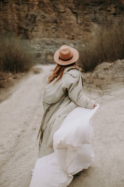 Dağlarda yürüyen şapkalı genç bir kadın 