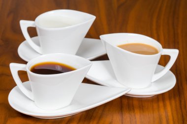 kahverengi ahşap masa üzerinde üç kahve fincanı