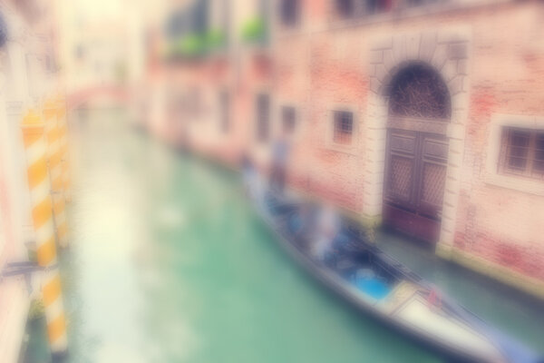 Defocused Background with Gondola with Tourists and a Gondolier in a narrow water canal between old buildings in Venice, Italy.