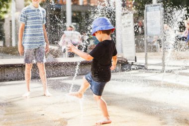 Sıcak bir yaz gününde çeşmede su jetiyle oynayan tatlı bir çocuk..