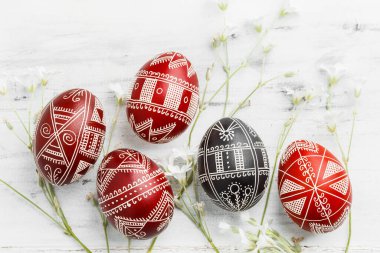 Kırmızı ve siyah el yapımı Paskalya Pysanka yumurtaları. Balmumuna dayanıklı boya tekniğiyle dekore edilmiş Ukrayna piranası. Beyaz tahta arkaplan