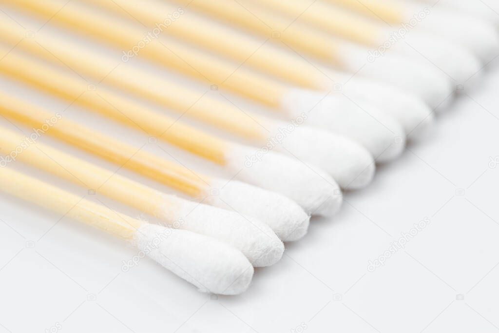 Wooden cotton swabs in a row on white background. Selective focus