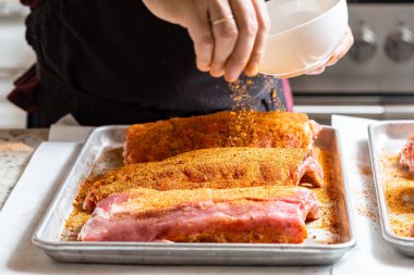 Erkek bir aşçının eli, çiğ et parçasına tuz ve baharat koyar. Ham St. Louis tarzı barbekü kaburgaları hazırlama süreci