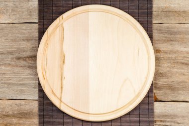 Arka planda ahşap pizza tahtası ve bambu masa örtüsü var.