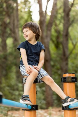 Paralel barlarda oynayan küçük bir erkek çocuk.