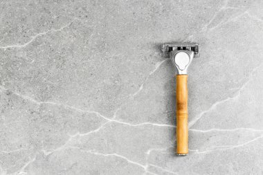Gri mermer arka planda tahta saplı tıraş bıçağı. Plastiksiz hijyen aleti. Damgalamak için boş alan