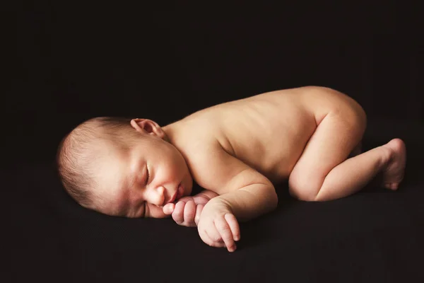 Durmiendo recién nacido desnudo bebé niño sobre fondo negro — Foto de Stock