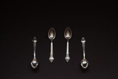 Siyah arka plan üzerine üst üste dört gümüş kaşık