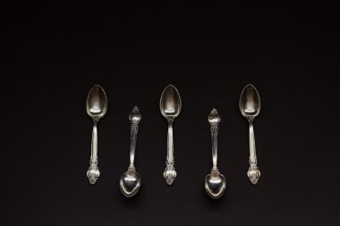 Siyah arka plan üzerine üst üste beş gümüş kaşık