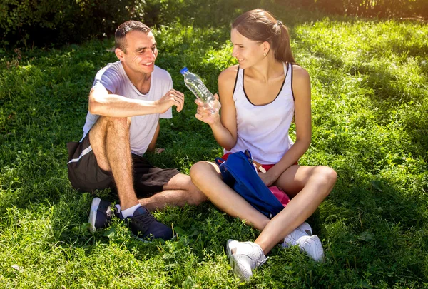 Young couple resting after training and drinking water — Stock Photo, Image