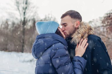 Erkek arkadaş ve kız arkadaş dışarıda öpüşüyor, karlı kış parkında yürüyor ve sarılıyorlar. Romantik bir randevu. Sevgili çift ormanda dinleniyor.