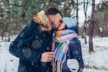 Sevgi dolu bir çift, kış ormanında kıvılcımlar yakıp öpüşüyor. Noel ve yeni yıl kutlaması. Kış mevsimsel tatilleri. İnsanlar eğleniyor.