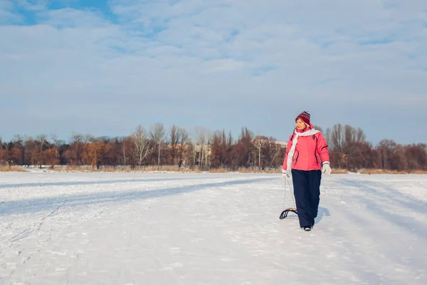 上了年纪的女人滑倒后带着雪橇 在冬日冰冻的河里玩得开心的女人 积极的生活方式 — 图库照片