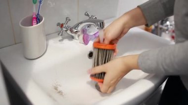Elektrik süpürgesi filtresi temizliyorum. Kadın süpürge filtresini evdeki lavaboda suyla yıkıyor. Ev işleri.