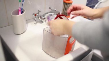 Elektrik süpürgesi filtresi ve toz için konteynır temizliyorum. Kadın süpürge filtresini banyo lavabosunda suyla yıkıyor.