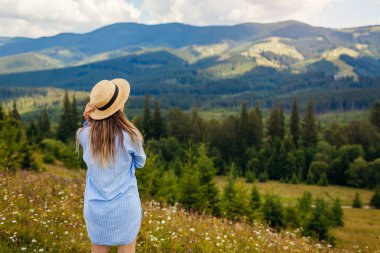 İlkbaharda Ukrayna 'da seyahat. Karpat dağlarına yolculuk. Çiçeklerin içinde dinlenen genç bayan turist manzaraya hayran. Yürüyüş