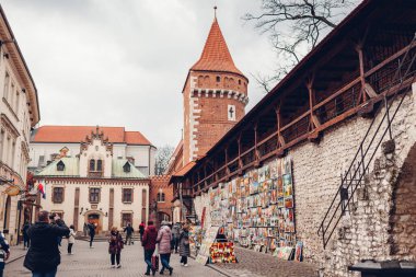 Krakow, Polonya - 8 Mart 2020: St. Florian 's Gate, Brama Florianska kulesi ve tabloların yanından geçen turistler