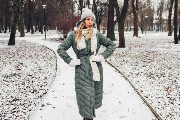 冬季女性时尚 在雪地的公园里 年轻的女人穿着长长的绿色外套 戴着围巾 现代保暖服装及配件 — 图库照片