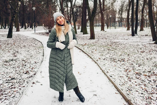 冬季时尚 在雪地的公园里 年轻的女人穿着长长的绿色外套 戴着围巾 手套和靴子 现代保暖服装及配件 — 图库照片
