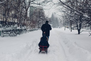 Dedem, kar yağarken küçük bir çocukla şehir caddesinde kızak çekiyor. Kışın açık hava aktiviteleri