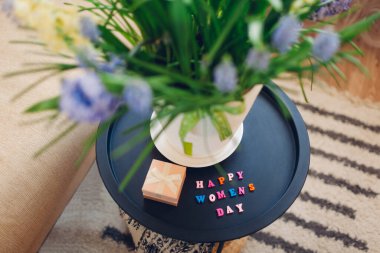 Mutlu Kadınlar Günü, 8 Mart hediyesi. Masada çiçek açan bahar çiçekleri ve evde hediye kutusuyla bırakılmış selamlar.