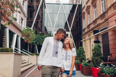Aşık genç bir çift Lviv şehrinde yürüyor geleneksel Ukraynalı işlemeli gömlekler giyiyorlar. Erkek ve kadın dışarıda sarılır.