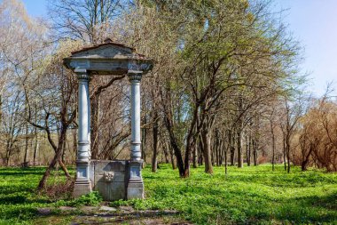 Ukrayna 'daki Olesko şatosunun yanındaki bahar parkında antik taş kemer ve sütunlar. Eski tarihi binaların mimari unsurları