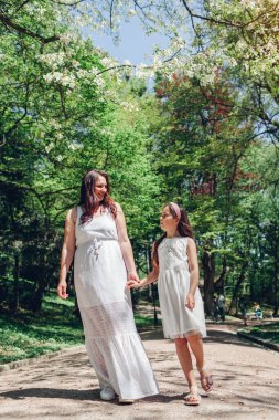 Anne kızıyla birlikte çiçek açan bahar parkında çiçek açan manolya ağacının altında yürüyor. Aile dışarıda dinlenir. El ele tutuşan kadın ve kız