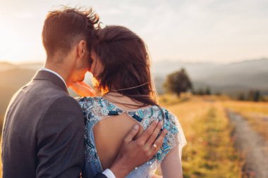 Genç, sevgi dolu bir çift gün batımında dağlarda sarılıyor. Yazın Karpatlar 'da mutlu gelin ve damadın portresi. Çıplak arka plan elbisesi