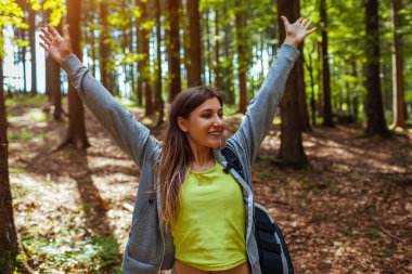 Karpatya dağlarında ormanda gezen bir turist kadın manzaranın tadını çıkarıyor. Mutlu gezgin kollarını kaldırıyor. Yazın Ukrayna 'da sırt çantasıyla seyahat etmek.