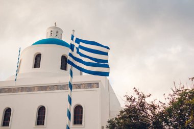 Santorini 'nin Yunanistan' ın Oia kentindeki mavi kubbeli ve Yunan bayrağı manzarası. Turizm, seyahat, yaz tatili.