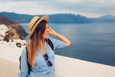 Santorini adasında yürüyen turist kadın, Yunanistan deniz manzarasının tadını çıkarıyor. Gezgin, Oia 'daki Caldera manzarasına hayran.