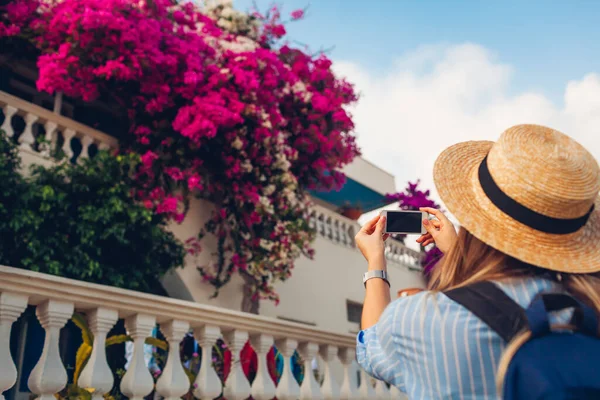 Жінка - мандрівник фотографує квітучі квітки буґенвілле на вулиці в Греції. Турист любить пейзаж. — стокове фото