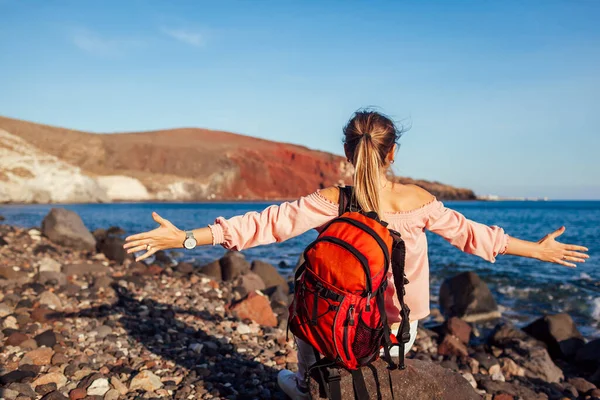 Мандрівниця з рюкзаком розслаблює руки на Червоному пляжі на острові Санторіні, Греція.. — стокове фото