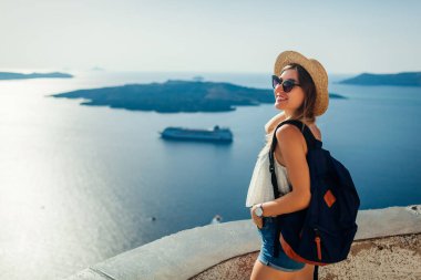 Santorini, Fira 'da Caldera deniz manzarasının tadını çıkaran kadın turist Ege denizi ve gemilerine bakıyor. Yaz tatili boyunca seyahat