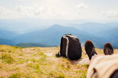 Karpat dağlarında yürüyüş. Yürüyüşçü sırt çantasında dinleniyor ve manzaranın tadını çıkarıyor. Yazın Ukrayna 'da seyahat. Yürüyüş ayakkabılarını kapat.