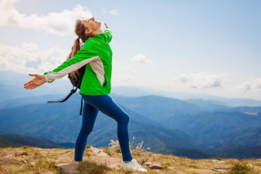 Karpat dağlarına yolculuk. Sırt çantasıyla gezen mutlu kadın turist Hoverla 'nın tepesinde kollarını kaldırarak manzaranın ve temiz havanın tadını çıkarıyor. Yazın Ukrayna 'da seyahat